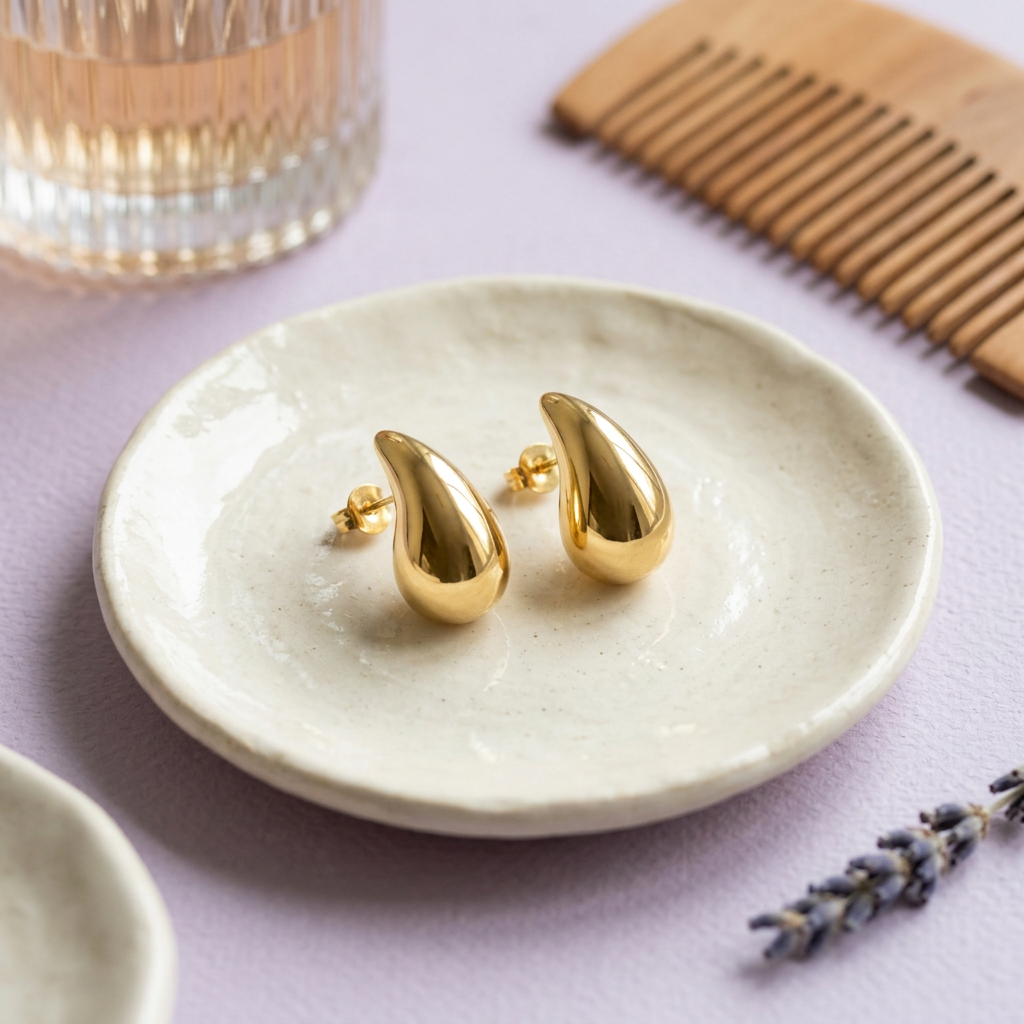 Gold-tone teardrop studs on ivory ceramic dish