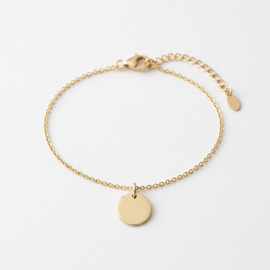 Fine gold-tone chain bracelet with smooth disc on white
