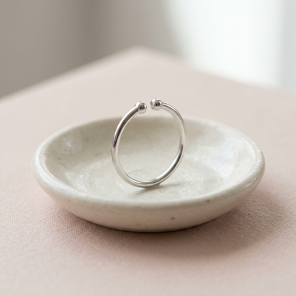 Silver-tone open ring on ivory ceramic dish