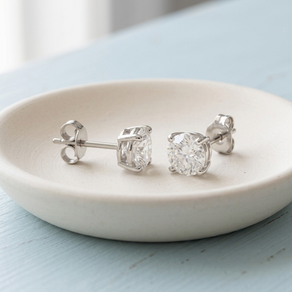 Silver-tone solitaire earrings on ivory ceramic dish