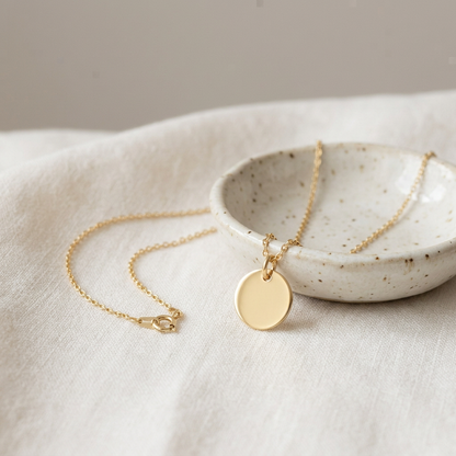 Disc necklace on ivory linen with ceramic dish