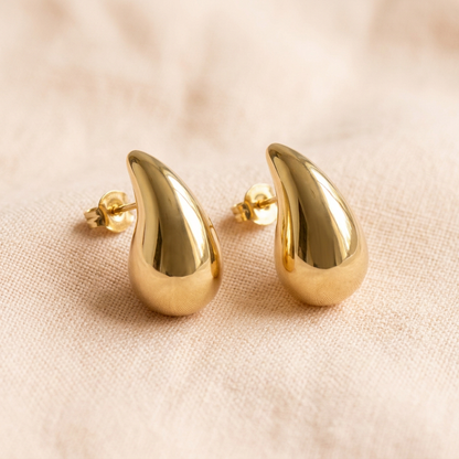 Teardrop earring pair on pale peach linen