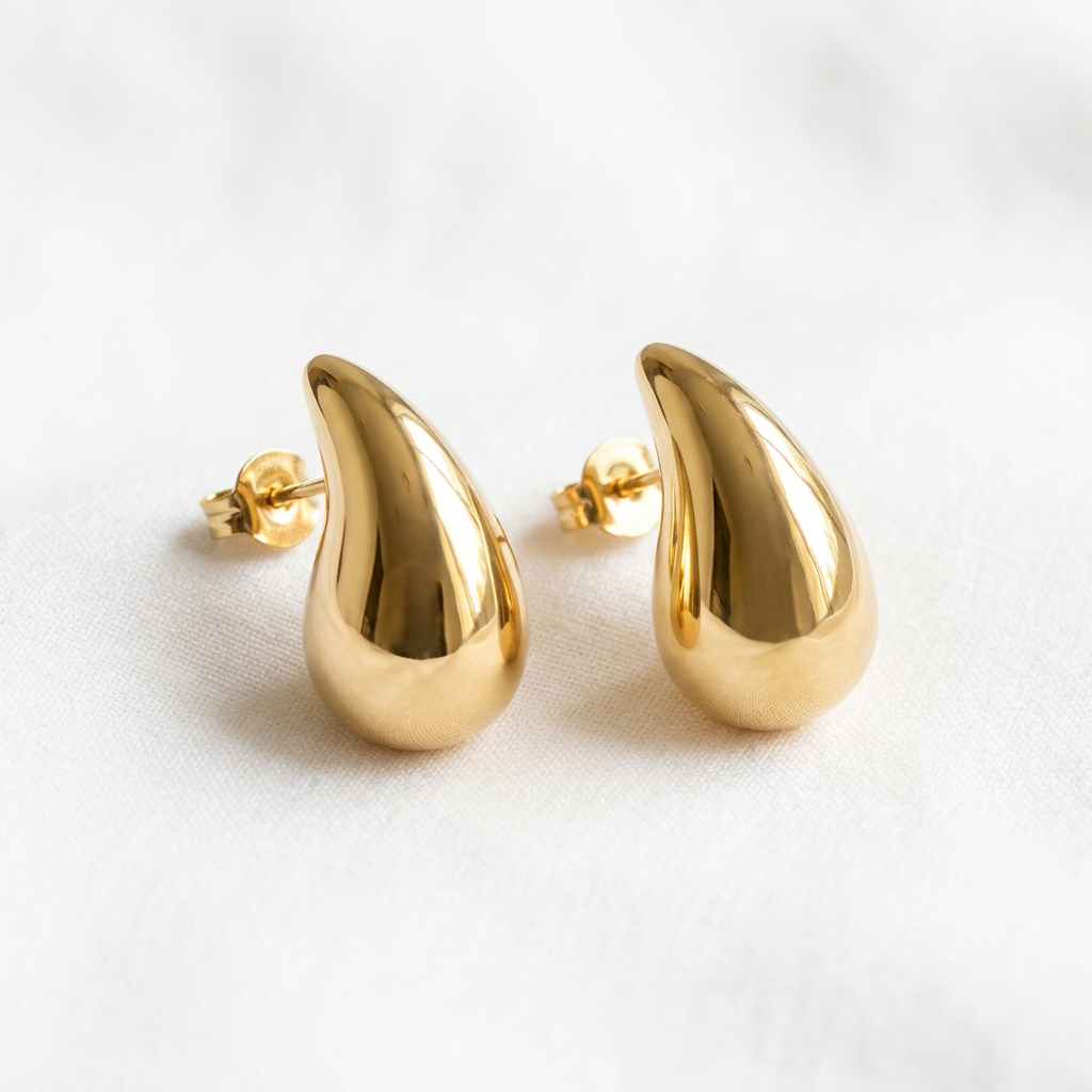 Matching sculpted gold-tone teardrop stud earrings on white