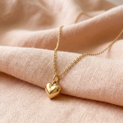 Gold-tone heart necklace on peach linen