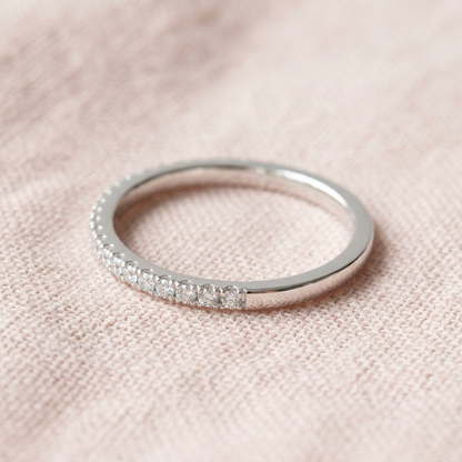 Fine clear-accent band ring on pale blush linen