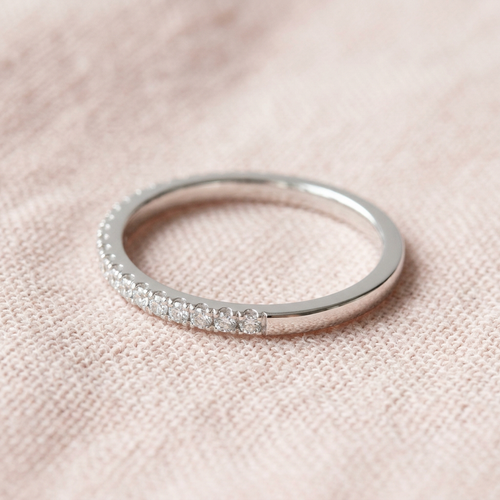 Fine clear-accent band ring on pale blush linen