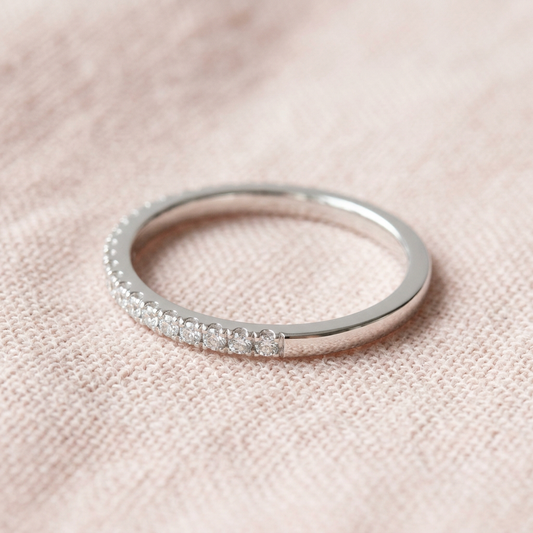 Fine clear-accent band ring on pale blush linen