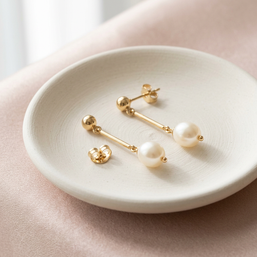 Pearl-style drop earrings on ivory ceramic dish