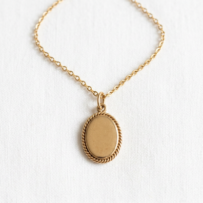 Gold-tone oval pendant necklace with rope-style border on white